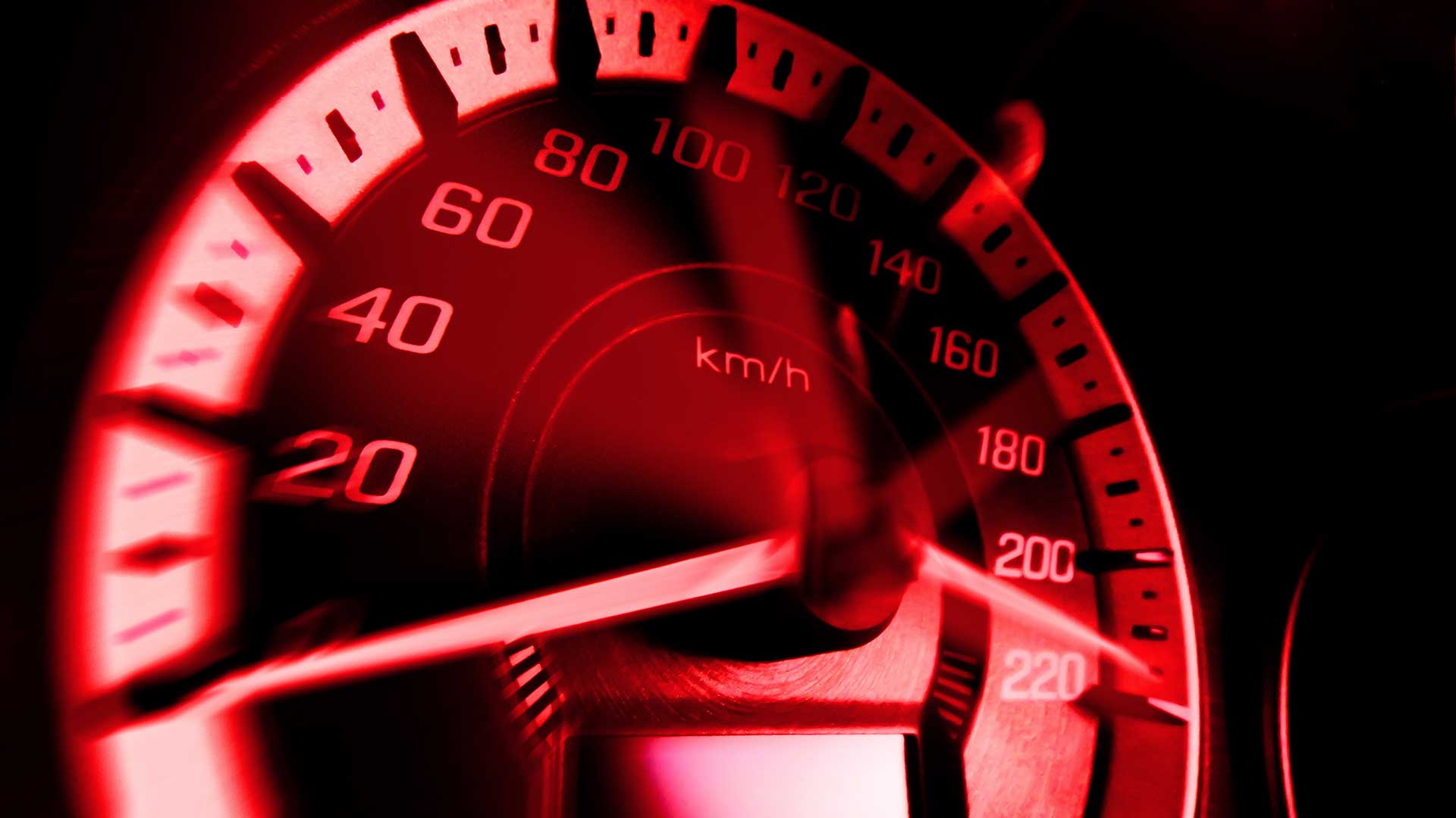 Close up shot of a speedometer in a racecar with red light speed at 220 Km/H.