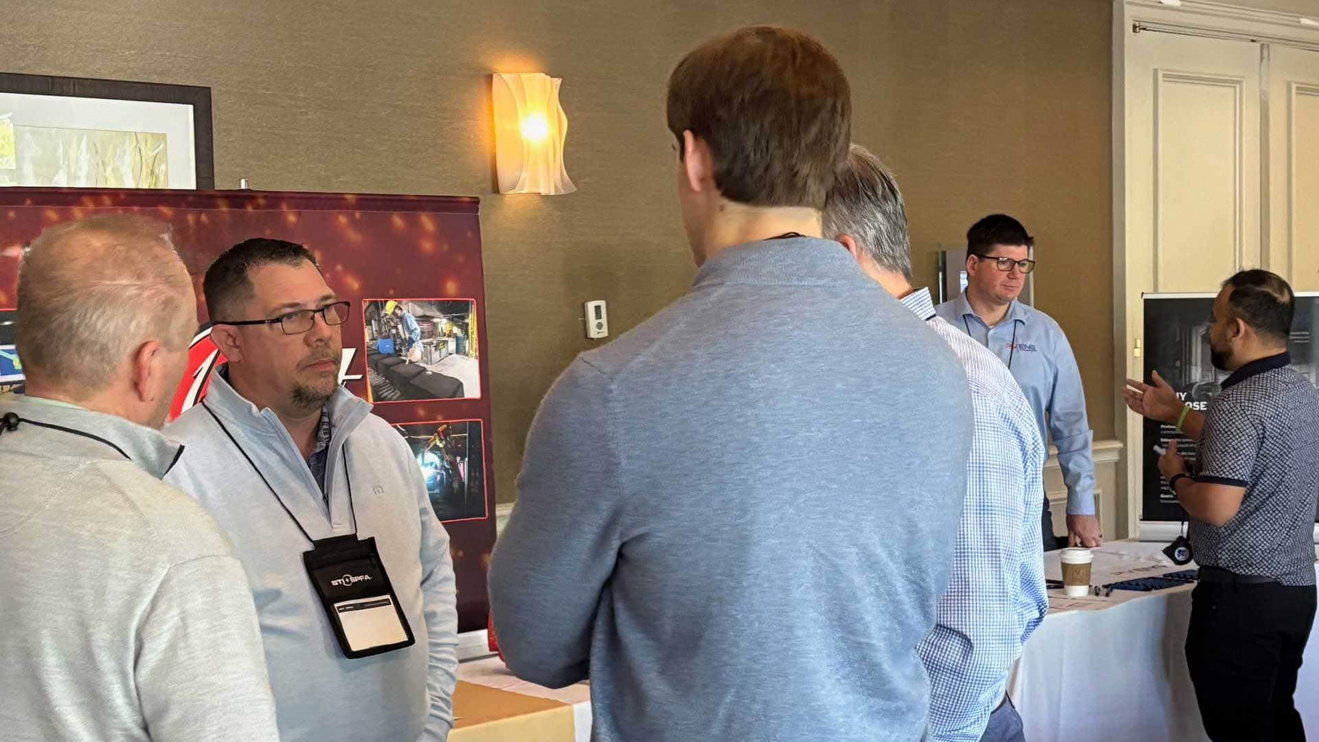 Attendees talking with exhibitors at sponsor tables during an event.