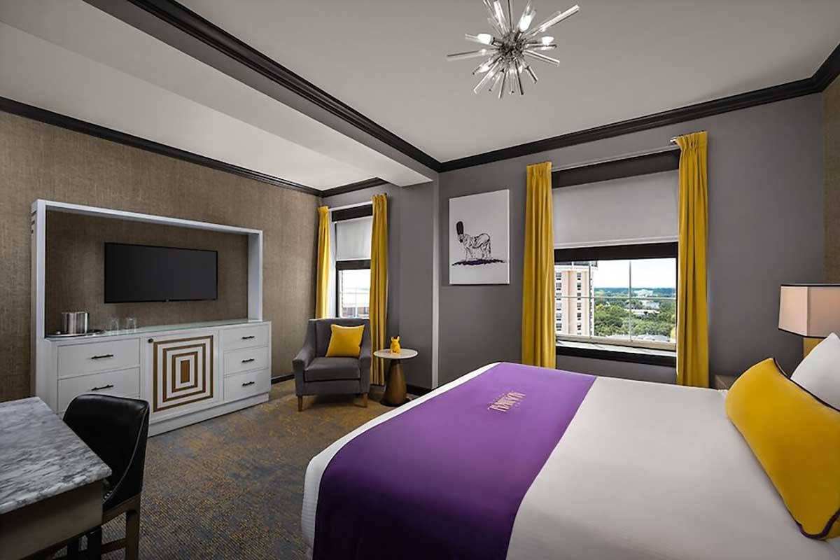 Guest room interior at The Admiral Hotel featuring a king bed, modern furnishings, seating area, and large windows.